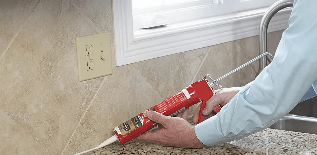 Handyman applying caulk along a kitchen backsplash and countertop seam in Myrtle Beach, SC