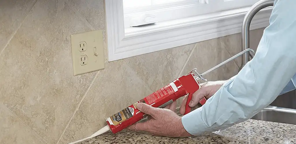 Handyman applying caulk along a kitchen backsplash and countertop seam in Myrtle Beach, SC