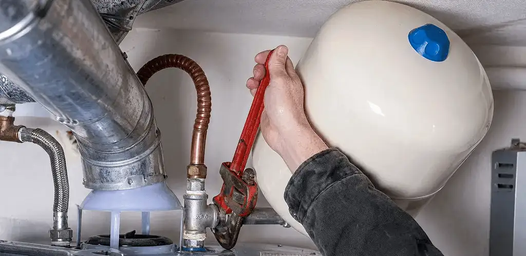 Water heater repair technician tightening plumbing connections near a tank unit in Myrtle Beach, SC