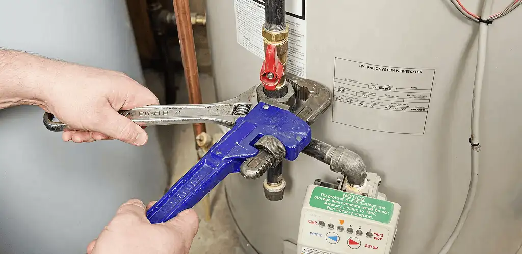 Water heater repair technician tightening the shutoff valve and supply line in Myrtle Beach, SC